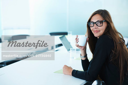 Portrait of businesswoman drinking coffee at conference table