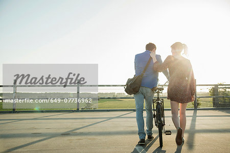 Young couple pushing bicycle in empty parking lot