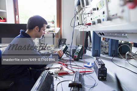 Male electrician repairing electronic equipment in workshop