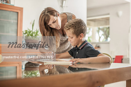 Mother and son looking down at homework at dining room table