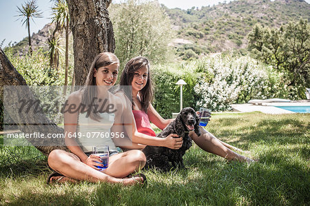 Portrait of two female friends with dog in holiday home garden, Capoterra, Sardinia, Italy