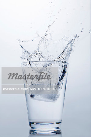 Ice cube splashing into glass of clear water Ice cube splashing into glass of clear water