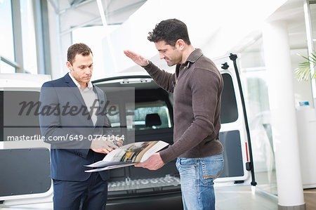 Customer questioning salesman in car dealership