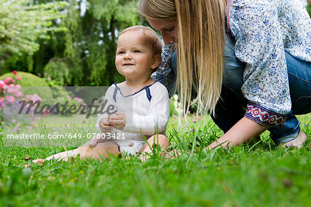 Mother with baby girl sitting on grass