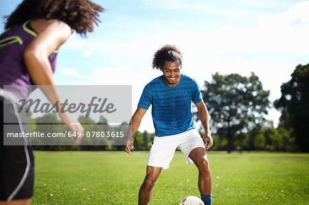 Young couple playing soccer together in park