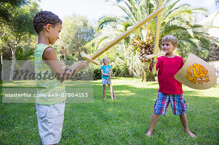 Three children in garden playing with toy swords