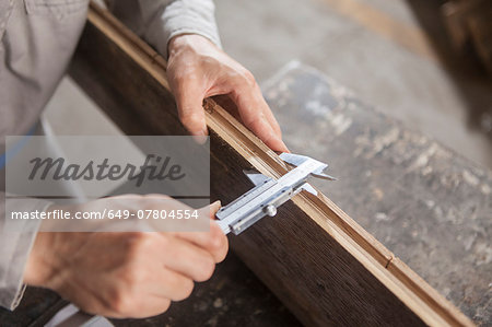 Carpenter measuring wood plank with vernier caliper in factory, Jiangsu, China