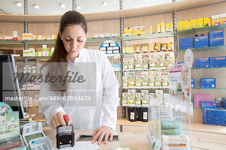 Pharmacist in pharmacy stamping prescription