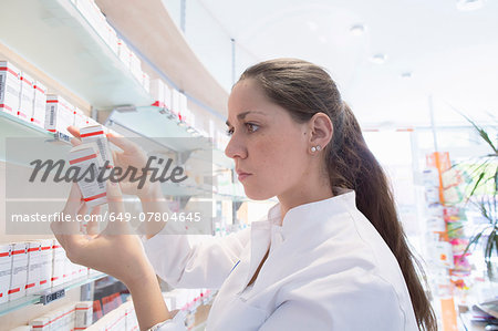 Pharmacist in pharmacy reading medicine box