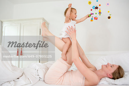 Mother lifting baby daughter on bed
