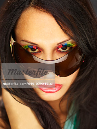 Young woman peeking over sunglasses with fake eyelashes
