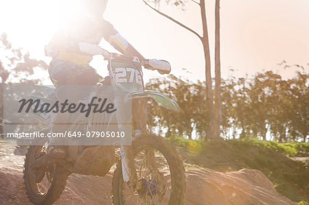 Cropped shot of young male motocross racer jumping mid air down mud hill