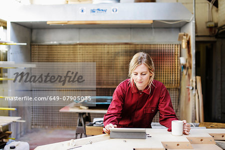 Young craftswoman using digital tablet in pipe organ workshop