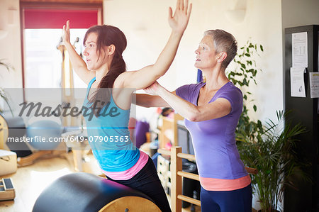 Female student leaning forward onto pilates barrel in pilates gym