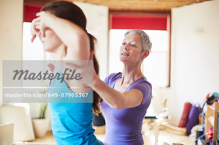 Young female student and tutor in pilates gym