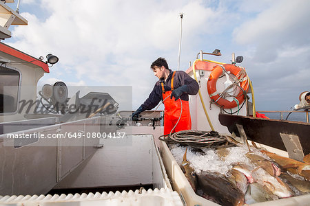 Fisherman puilling up fishing line on fishing boat
