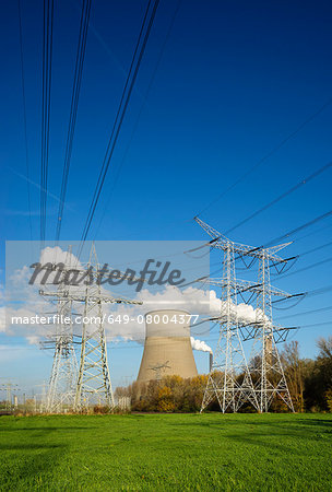 View of electrical towers in front of cooling towers and smoke stacks