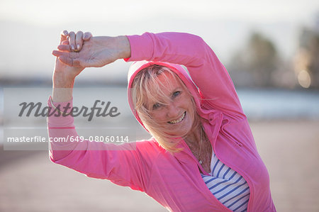 Senior woman stretching by beach