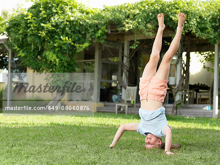 Girl doing headstand in garden