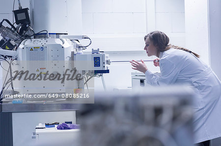 Young female scientist in lab using scanning electron microscope