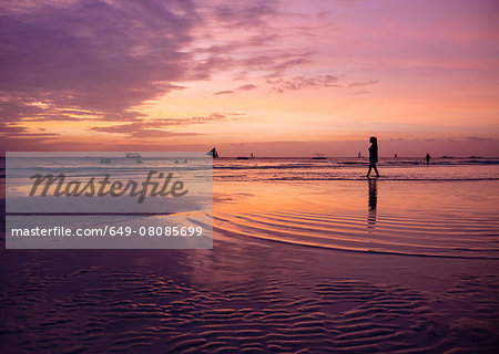 Silhouetted young woman on beach at sunset, Boracay Island, Visayas, Philippines