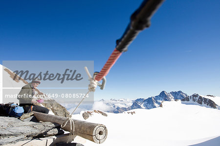 Male hiker eating snacks on viewing platform, Jungfrauchjoch, Grindelwald, Switzerland