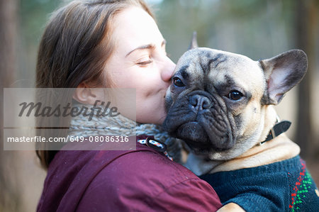 Portrait of wise dog being carried through forest by young woman