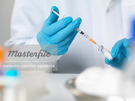 Doctor preparing a vaccine to inject into a patient Doctor preparing a vaccine to inject into a patient