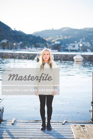 Portrait of young woman standing on lakeside pier, Lake Como, Italy