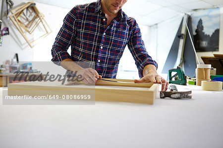 Mid adult man measuring frame on workbench in picture framers workshop