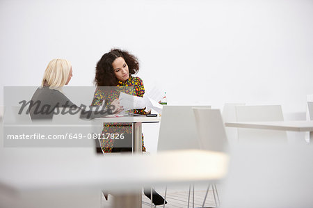 Two businesswomen checking paperwork at office meeting
