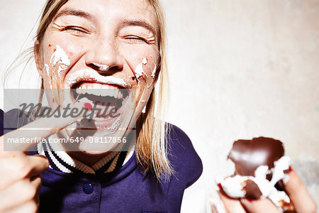 Close up studio shot of young woman with face covered in chocolate marshmallow