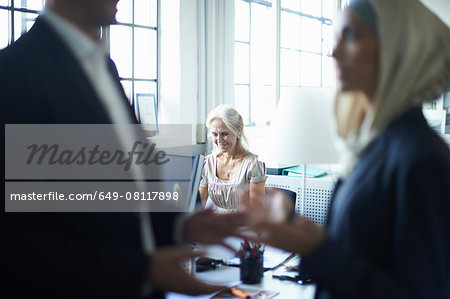 Close up of mature businessman talking to young businesswoman in office