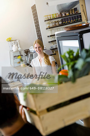 Man delivering crate of vegetables to shopkeeper