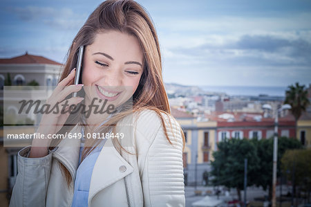 Young woman on rooftop chatting on smartphone, Cagliari, Sardinia, Italy