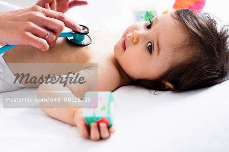 Paediatrician checking baby boy's heart using stethoscope