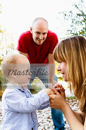 Son face to face with mother, holding hands, while father looks on