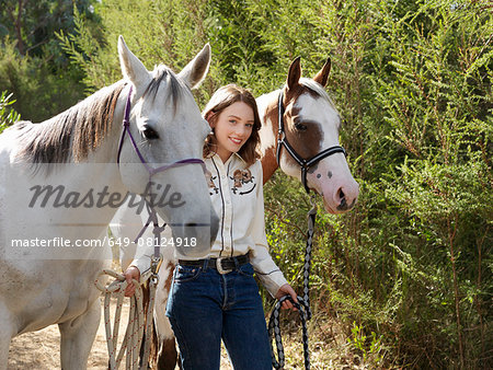 Portrait of teenage girl leading two horses