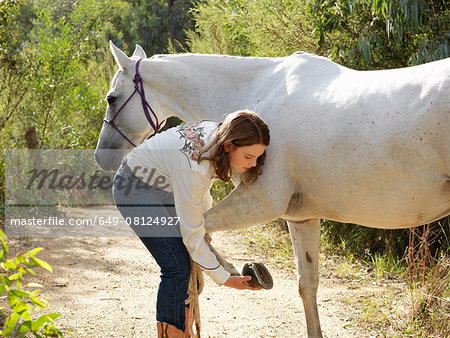 Teenage girl checking horse hoof