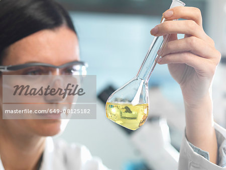 Chemist looking at solution in flask during research experiment