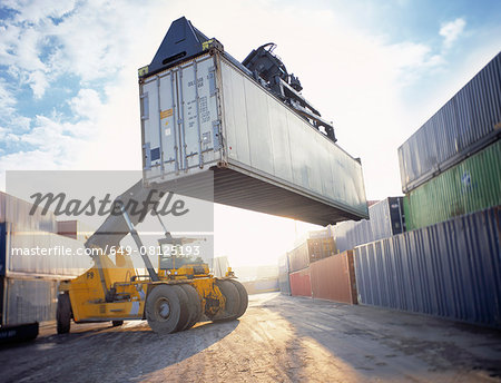 Stacker lifting shipping container in port, Grimsby, England, United Kingdom