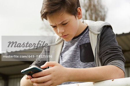 Anxious teenage boy reading smartphone text message Anxious teenage boy reading smartphone text message