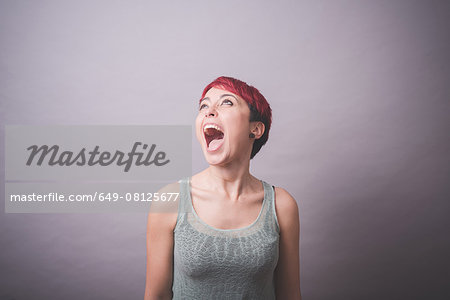 Studio portrait of young woman with short pink hair shouting