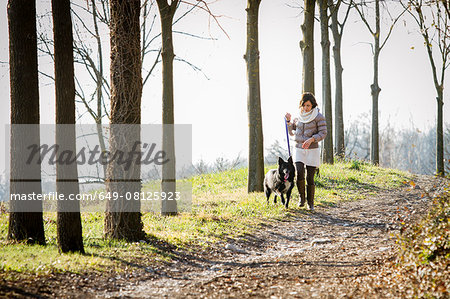 Mid adult woman walking her dog on dirt path