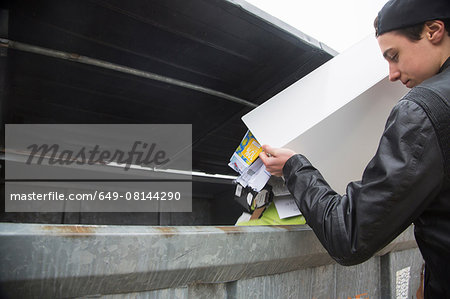 Teenage boy emptying bin with paper waste to recycling bin