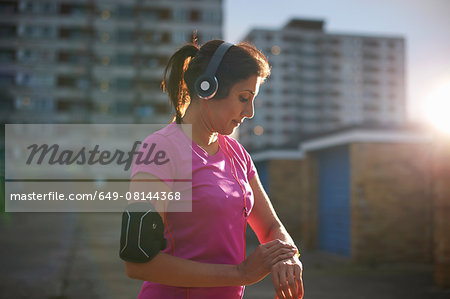 Mature female runner checking wrist watch at dusk