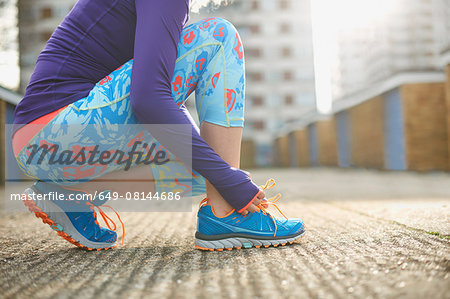 Cropped view of woman bending to tie sports training shoe lace Cropped view of woman bending to tie sports training shoe lace