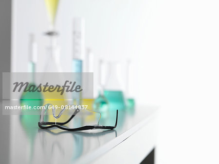 Safety glasses on laboratory bench with a chemical experiment in background