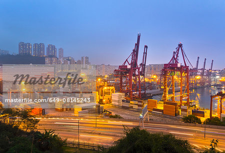 Cargo containers and loading cranes illuminated at night, Hong Kong, China