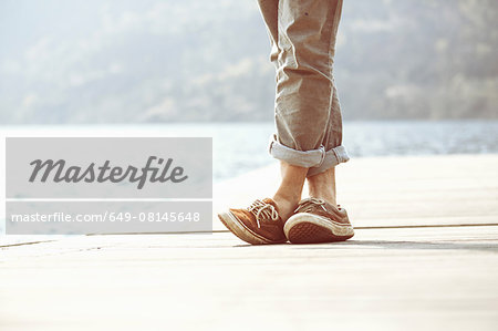 Feet of young man standing on pier, Lake Mergozzo, Verbania, Piemonte, Italy